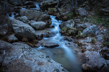 Naklejka na ściany i meble River water flows among the rocks and forms small waterfalls, Rascafría, Madrid, Spain