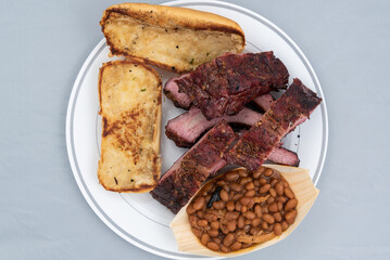 Overhead view of  meal of half slab of ribs, baked beans, and butter toasted bread will taste as delicious as it looks.