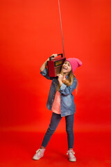 Party time. Caucasian little girl's portrait isolated on red studio background. Cute stylish model. Concept of human emotions, facial expression, sales, ad, childhood, education. Copyspace.