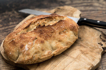 White Bread. Isolated. Homemade white bread loaf with bread knife on a wooden cutting board. Stock Image
