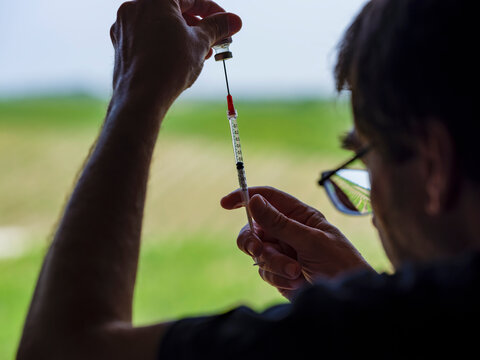 Person Filling A Syringe With The Covid 19 Vaccine