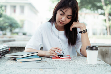 Obraz premium University student listen to musich with earphones and smartphone at park.