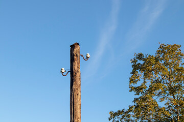 Old wooden power transmission pole with two ceramic insulators