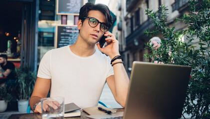 Young smart man speaking on smartphone at cafe in Barcelona city