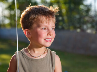 Portrait of a shirtless smiling child lit by the sun on a summer day.