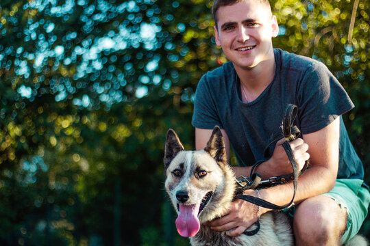 Cropped image of handsome young man with Siberian Husky dog outdoors. Man on a green grass with dog. Cynologist. Concept friendship. Millennial in a moment of relaxation with his dog. Selective focus