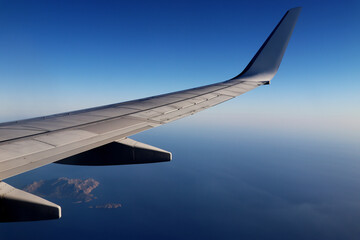 Fototapeta na wymiar Plane wing over the ocean with islands