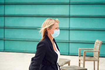 Mature Businesswoman Wearing PPE Face Mask Walking Outdoors In Street During Health Pandemic