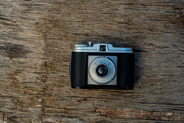An old film camera lies on a wooden surface.