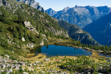 Lake and a red tent in the mountains of Ticino on a summers mornig.