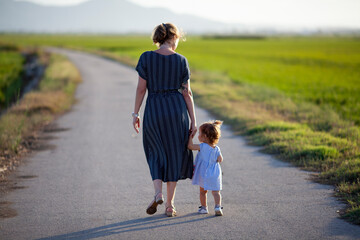Madre e hija paseando por camino solitario al atardecer