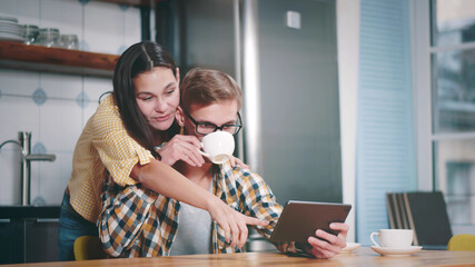 Young Couple Using Tablet PC in Kitchen at Home during Breakfast
