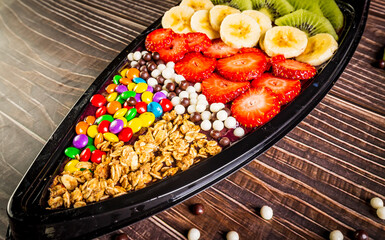 Acai frozen with banana, kiwi fruit, granola and candies for share. A boat for share.