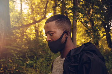 Fit male African jogger wearing face mask