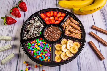 Acai frozen with banana, granola, chocolate and candies for share. A roulette for share.