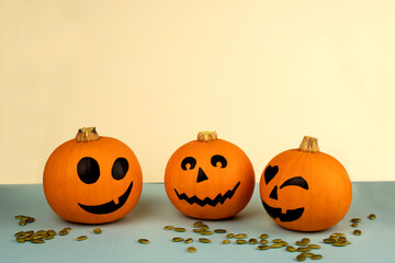 Little pumpkins with painted faces for Halloween with spiders on the net on orange and black background