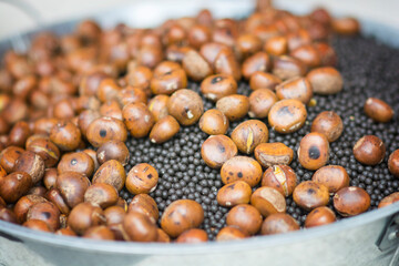 Close up view of roasted Chestnuts (Castanea sativa) in a metal ball with black sand.  Chengdu, Sichuan, China