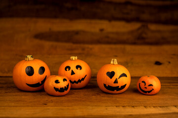 Little pumpkins and mandarines with painted faces for Halloween on wooden background