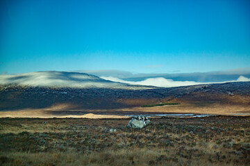 Scottish Highlands in fall. View on valley and mountains. Peaks with snow. Blue sky