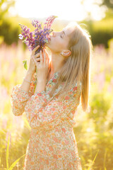 Portrait of beautiful blonde woman with bouquet of lupin flowers in her hands