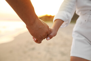 Lovely couple holding hands on beach, closeup