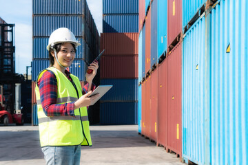 Engineer woman or Foreman manager in container depot working with digital tablet and walkie talkie for control and checking industrial container yard