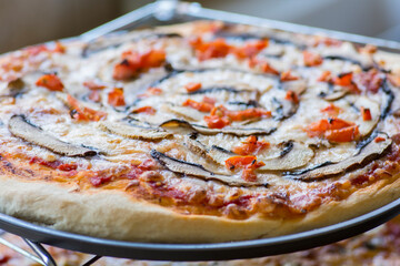 Close up view of a Pizza with mushrooms, peppers and tomatoes