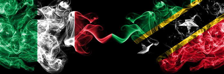 Italy vs Saint Kitts and Nevis smoky mystic flags placed side by side. Thick colored silky abstract smoke flags of Italian and Saint Kitts and Nevis