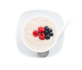 Oatmeal porridge with raspberries and blueberries on a white background, healthy Breakfast