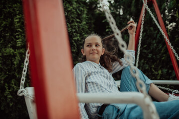 Happy laughing girl posing on swing in sunset summer