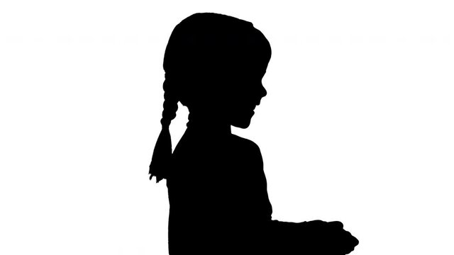 Silhouette Smiling little girl play videogame holding joystick in her hands.