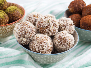 Home made vegan energy protein balls with coconut flakes, almond butter, oats, nuts, dates, dried fruit, flax and hemp seeds served in bowl on turquoise napkin. Closeup