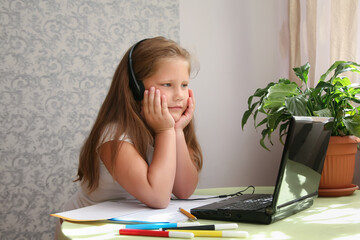 Focused kid self isolation wearing headphones using laptop in cafe, writing notes,student girl...