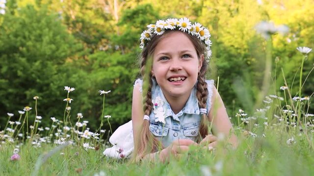 a cute little girl lying on green grass. camomiles. daisies. the child strongly laughs