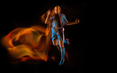 In fire. Football or soccer player on black studio background in mixed light. Young male sportive model training in action. Kicking ball, attacking, catching. Concept of sport, competition, winning.
