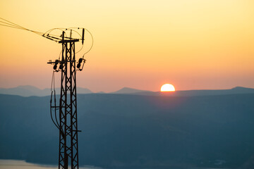 High voltage towers on coast at sunset