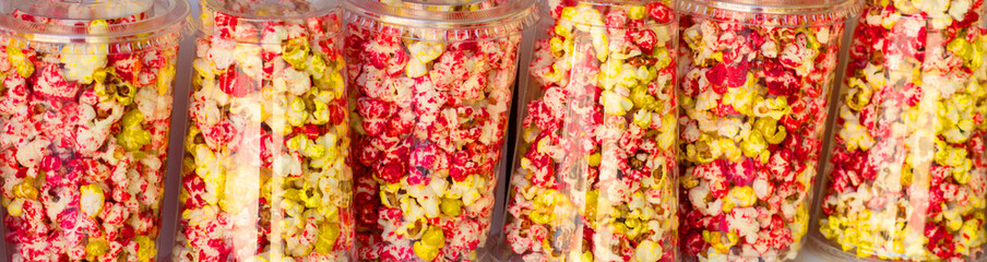 Glasses with a colored popcorn, snack and cinema concept, banner