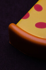 Slice of pizza. Toy plastic fruits and food isolated on black backgound.