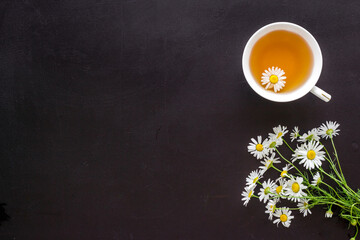 Obraz na płótnie Canvas Mug of chamomile tea with fresh flowers top view