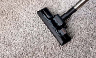 Partial view of a vacuum cleaner on a gray carpet