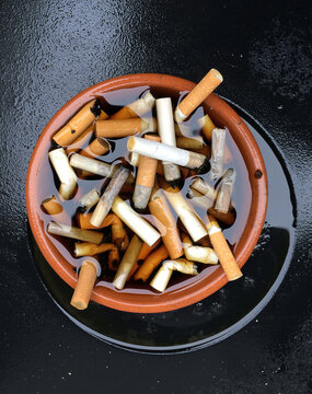 A filthy dirty ash tray full of cigarette butts. Cancer causing carcinogenic dirty smokers. Unhealthy lung disease and Chronic obstructive pulmonary disease