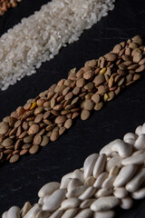 Flat lay composition with different types of grains and cereals on black background