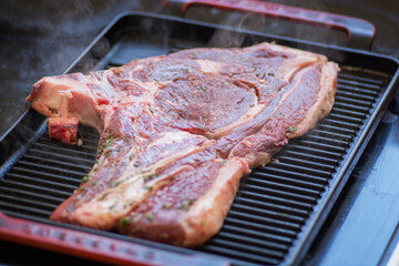Close up view of a raw steak, a Sirloin cut, being grilled on a grilling pan
