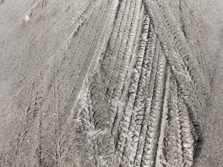 Tyre track and human footprint on sand texture background. Traces of off-road tires. Cracked earth on country road with traces of tires, cars, cracks and dirt. To use as background