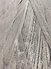 Tyre track and human footprint on sand texture background. Traces of off-road tires. Cracked earth on country road with traces of tires, cars, cracks and dirt. To use as background