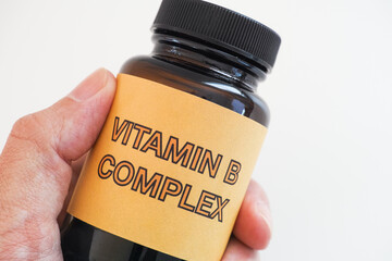 Person holding a bottle of Vitamin B Complex