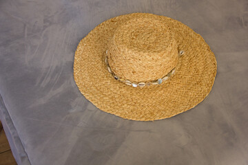 Fototapeta na wymiar close-up straw hat lies on a gray sofa in boho style interior, travel concept, free space