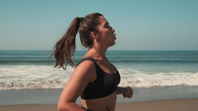 Attractive woman jogging along golden seacoast