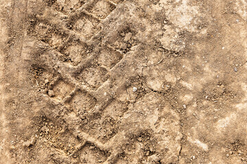Tyre track and human footprint on sand texture background. Traces of off-road tires. Cracked earth on country road with traces of tires, cars, cracks and dirt. To use as background