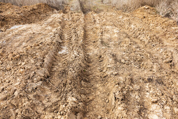Tyre track and human footprint on sand texture background. Traces of off-road tires. Cracked earth on country road with traces of tires, cars, cracks and dirt. To use as background